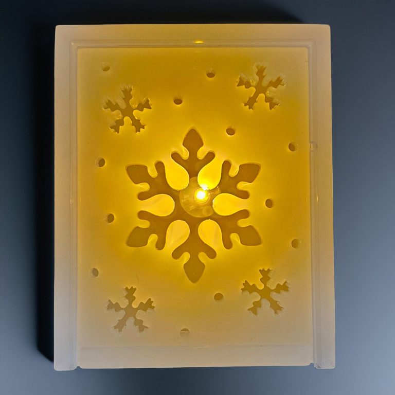Gelbe LED-Lampe mit Schneeflocken-Muster auf weißem Hintergrund.